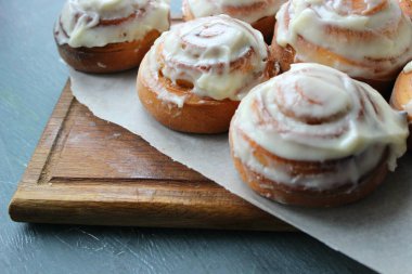 Güzel taze tarçın ruloları ahşap grunge doku masasına yakın çekim. Ev yapımı kekler, Cinnabon. Beyaz çay tabağında bir fincan çay, tarçın çubukları. Lezzetli Kahvaltı Büfesi.