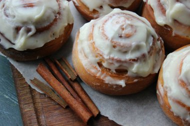 Güzel taze tarçın ruloları ahşap grunge doku masasına yakın çekim. Ev yapımı kekler, Cinnabon. Beyaz çay tabağında bir fincan çay, tarçın çubukları. Lezzetli Kahvaltı Büfesi.