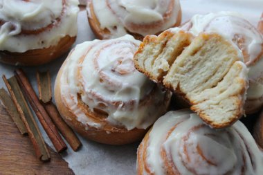 Güzel taze tarçın ruloları ahşap grunge doku masasına yakın çekim. Ev yapımı kekler, Cinnabon. Beyaz çay tabağında bir fincan çay, tarçın çubukları. Lezzetli Kahvaltı Büfesi.
