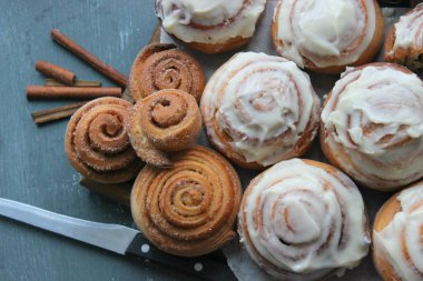 Güzel taze tarçın ruloları ahşap grunge doku masasına yakın çekim. Ev yapımı kekler, Cinnabon. Beyaz çay tabağında bir fincan çay, tarçın çubukları. Lezzetli Kahvaltı Büfesi.