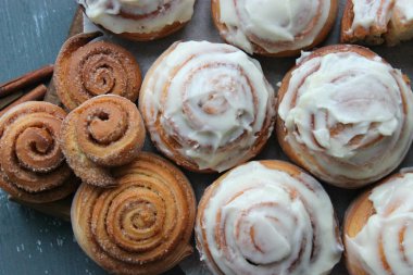 Güzel taze tarçın ruloları ahşap grunge doku masasına yakın çekim. Ev yapımı kekler, Cinnabon. Beyaz çay tabağında bir fincan çay, tarçın çubukları. Lezzetli Kahvaltı Büfesi.