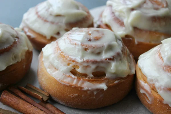 Güzel taze tarçın ruloları ahşap grunge doku masasına yakın çekim. Ev yapımı kekler, Cinnabon. Beyaz çay tabağında bir fincan çay, tarçın çubukları. Lezzetli Kahvaltı Büfesi.