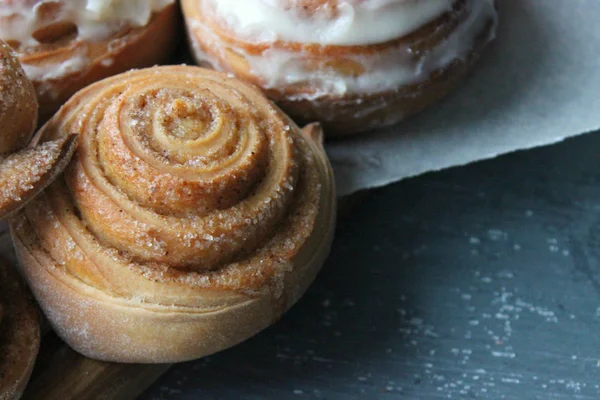 Güzel taze tarçın ruloları ahşap grunge doku masasına yakın çekim. Ev yapımı kekler, Cinnabon. Beyaz çay tabağında bir fincan çay, tarçın çubukları. Lezzetli Kahvaltı Büfesi.
