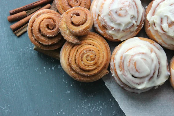 Güzel taze tarçın ruloları ahşap grunge doku masasına yakın çekim. Ev yapımı kekler, Cinnabon. Beyaz çay tabağında bir fincan çay, tarçın çubukları. Lezzetli Kahvaltı Büfesi.