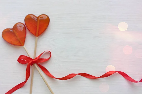 Romantic Valentine`s day background. Lollipops in the shape of heart close up on white background. Copy space.The concept of Valentine`s day. Pink bokeh, stars, love. Beautiful background.