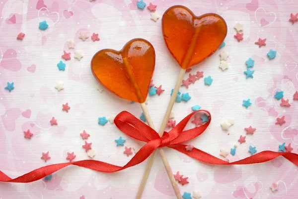 Romantic Valentine`s day background. Lollipops in the shape of heart close up on white background. Copy space.The concept of Valentine`s day. Pink bokeh, stars, love. Beautiful background.