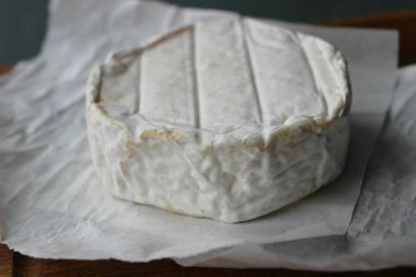 Camembert peyniri yakın çekim. Arka plan ağaç beyaz kağıt üzerinde yuvarlak Camembert peyniri. Gurme peynir, peynir tabağı, şarap yemek. Camembert peyniri. Taze brie peyniri ve fındık, bir ahşap tahta kesim tatlım ve bırakır. İtalyan, Fransız chee