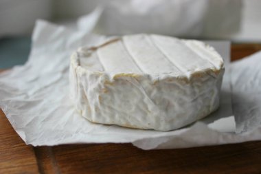 Camembert peyniri yakın çekim. Arka plan ağaç beyaz kağıt üzerinde yuvarlak Camembert peyniri. Gurme peynir, peynir tabağı, şarap yemek. Camembert peyniri. Taze brie peyniri ve fındık, bir ahşap tahta kesim tatlım ve bırakır. İtalyan, Fransız chee