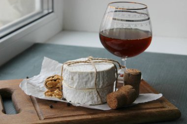 Camembert peyniri yakın çekim. Arka plan ağaç beyaz kağıt üzerinde yuvarlak Camembert peyniri. Gurme peynir, peynir tabağı, şarap yemek. Camembert peyniri. Taze brie peyniri ve fındık, bir ahşap tahta kesim tatlım ve bırakır. İtalyan, Fransız chee