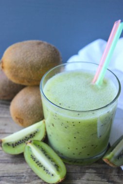 Mavi ahşap bir masa üzerinde taze kivi dilimleri yanında bir bardak kivi smoothies. meyve içeceği.kopya alanı