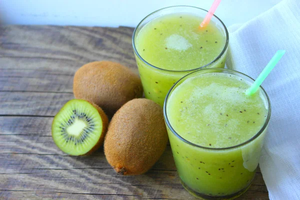 Summer refreshing drink. Healthy food, vegetarianism. Kiwi smoothie in a glass next to fresh kiwi slices on a wooden table. fruit drink.copy space