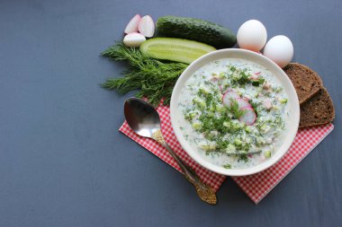 Okroshka seramik bir kase geleneksel bir Rus yaz soğuk çorba. Malzemeler patates, turp, salatalık, dereotu, yumurta, kefir (yoğurt), sosis. Tahta bir masada yazlık yoğurt soğuk çorbası. Seçici odaklama, kopyalama alanı.