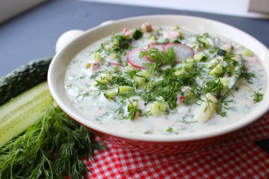 Okroshka seramik bir kase geleneksel bir Rus yaz soğuk çorba. Malzemeler patates, turp, salatalık, dereotu, yumurta, kefir (yoğurt), sosis. Tahta bir masada yazlık yoğurt soğuk çorbası. Seçici odaklama, kopyalama alanı.