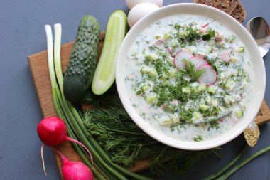 Okroshka seramik bir kase geleneksel bir Rus yaz soğuk çorba. Malzemeler patates, turp, salatalık, dereotu, yumurta, kefir (yoğurt), sosis. Tahta bir masada yazlık yoğurt soğuk çorbası. Seçici odaklama, kopyalama alanı.