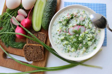 Okroshka seramik bir kase geleneksel bir Rus yaz soğuk çorba. Malzemeler patates, turp, salatalık, dereotu, yumurta, kefir yoğurt, sosis. Tahta bir masada yazlık yoğurt soğuk çorbası. Seçici odaklama, kopyalama alanı.