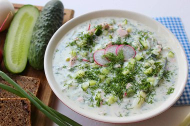 Okroshka seramik bir kase geleneksel bir Rus yaz soğuk çorba. Malzemeler patates, turp, salatalık, dereotu, yumurta, kefir yoğurt, sosis. Tahta bir masada yazlık yoğurt soğuk çorbası. Seçici odaklama, kopyalama alanı.