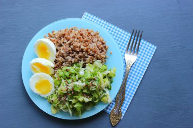 Sebzeli karabuğday. Ahşap bir arka plan üzerinde. Yukarıdan manzara. Kopya alanı. Koyu bir arka plan üzerinde yumurta, salata ve karabuğday lapası ile Sağlıklı Kahvaltı. Doğru beslenme. Diyet menüsü.