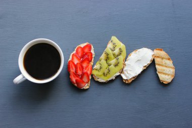 Bruschetta süzme peynir ve taze çilek ve kivi çilek tost kepekli ekmek ile. Yumuşak peynirli fransız tostu. Yaz pikniği zamanı, ahşap rustik arka planda vejetaryen sandviçler. Kopya alanı. Sağlıklı beslenme kavramı.