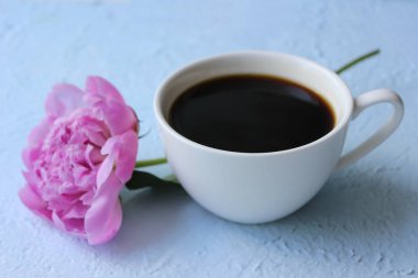 Güzel pembe şakayık ve hafif bir arka plan üzerinde bir fincan kahve. Kopyalama alanı.