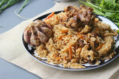 The concept of Oriental cuisine. Homemade Uzbek lamb pilaf is served on a round platter.  Copy space. clipart