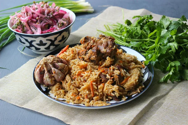 Doğu mutfağı kavramı. Ev yapımı Özbek kuzu pilavı yuvarlak bir tabakta servis edilir. Kopyalama alanı.