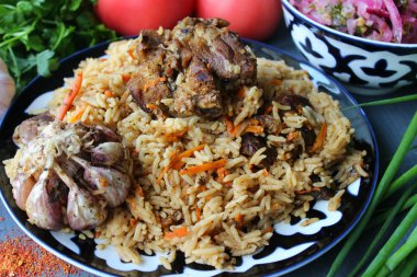 Pilav et ve baharat tabağının üzerinde.tahta bir arka plan üzerinde bir tabakta pilav, üst görünümü. Doğu mutfağı kavramı. Ev yapımı Özbek kuzu pilavı dökme demir tencerede servis edilir. Kopya alanı. Oryantal ornamen ile bir tabakta pilav ve malzemeler