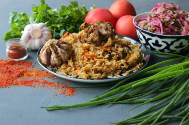 Pilav et ve baharat tabağının üzerinde.tahta bir arka plan üzerinde bir tabakta pilav, üst görünümü. Doğu mutfağı kavramı. Ev yapımı Özbek kuzu pilavı dökme demir tencerede servis edilir. Kopya alanı. Oryantal ornamen ile bir tabakta pilav ve malzemeler