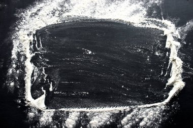 Beyaz buğday unu siyah masaya serpilir. Siyah arka plan üzerinde pişirme kavramı, kopya alanı ile un serpin.