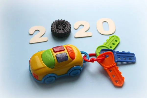 2020. Numaraları 2020 ve anahtarları ile bir Çocuk oyuncak araba. Yeni 2020 kavramı. Arabadan oyuncak anahtarlık. Anahtarlıklı çok renkli anahtar. Oyuncak arabadan kanca mavi bir arka plan üzerinde izole.