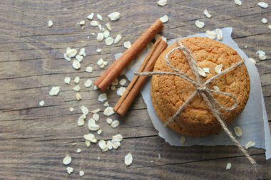 Eski ahşap bir masada ev yapımı yulaf ezmeli kurabiye ler ve bir fincan çay, rustik tarzı. Yulaf ezmesi ve tarçın çubukları. Kopya alanı. Yukarıdan görünüm.