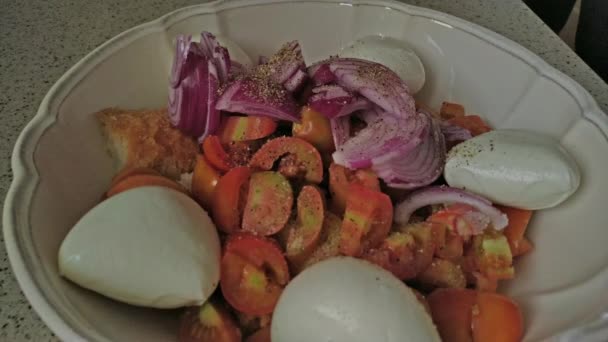 妇女加入盐 牛油和橄榄油在沙拉白碗 准备意大利沙拉潘扎内拉面包 番茄和莫扎雷拉 — 图库视频影像