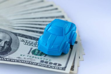 Bir mavi araba rakam yüz dolar faturaları ile kaplı bir tablo üzerinde duruyor. Konsept reklam kredi, teminat, rehin, Kiralık Araba. Para arabalar kavramı ya da fikir.