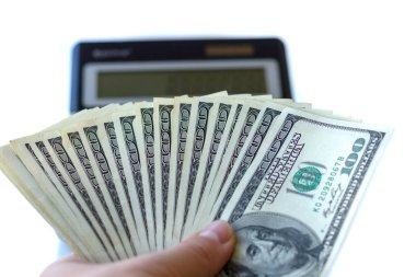 Bir adam bir yüz dolarlık banknot bir açık renkli w üzerinde tutar.