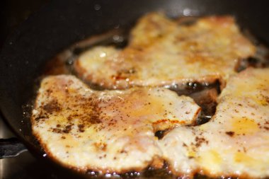 Evde fotoğraf et. Yumurta hamuru domuz pirzolası ve ekmek kırıntıları bir cızırtılı ayçiçeği yağı bir tavada yanmış.