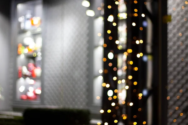 Abstract christmas lights shop windows. Bright circles bokeh from the lights of night windows. Illumination on windows, defocus and blur. Bright Christmas tree garlands for cards.