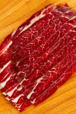 Güzel kokulu sulu pastırma ile baharat akasya dan Doğrama tahtası üzerinde kurumuş. Üstten görünüm. Düz yatıyordu. Et pastırma ile çizgili. Büyük iştah açıcı jambon. Kitap yönlendirme.