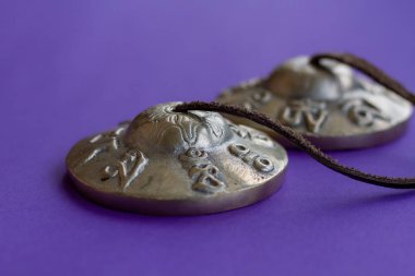 Tibet Tingsha: zenginlik ve refah deri şerit ile vücut üzerinde sekiz kutsal sembolleri ile bir müzik aleti. Mor bir arka plan üzerinde karatal. Seçici odak.