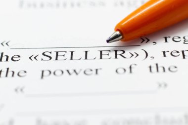 Bir sözleşmenin parçası bir tükenmez kalemi kağıdına basılır. Macrophoto Word satıcı yakın çekim. Alıcı ve satıcı bir sözleşme kağıt üzerinde yapılmış. Seçici odak.