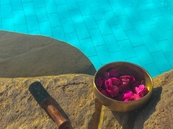 Bronze sound bowl of Tibetan medicine on the shore of the pool stands on an ancient stone. Tibetan healing therapy with a bronze singing bowl, a bowl for harmony and balance.