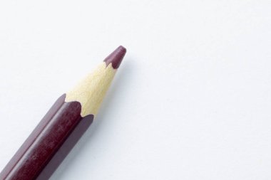 Kahverengi kalem sol alt köşesindeki beyaz kağıt üzerinde yalan söylüyor. Beyaz bir kalem kadeh makro yakın çekim.