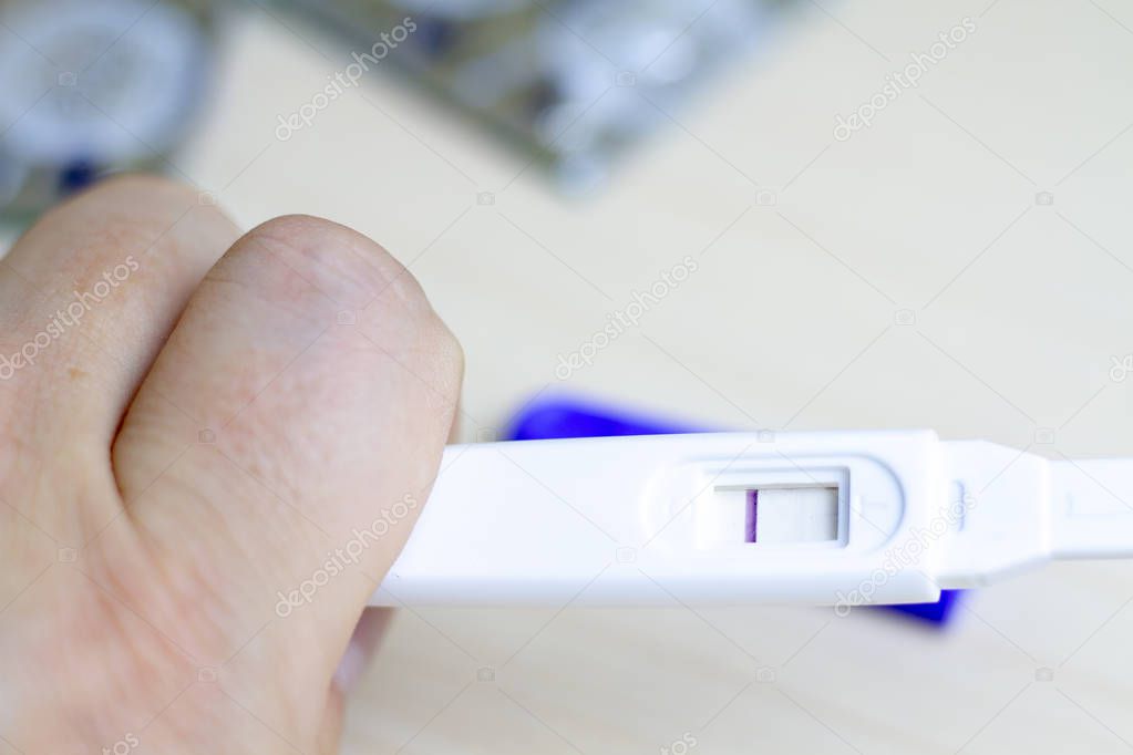 A man holds in his hand a pregnancy test with one strip. The con