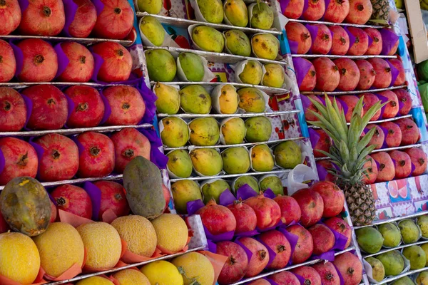 Спелые восточные фрукты находятся на прилавке восточного базара. Гранаты, дыни, манго, папайя, ананас. Спелые фрукты на столе. Покупая спелые фрукты на базаре . — стоковое фото