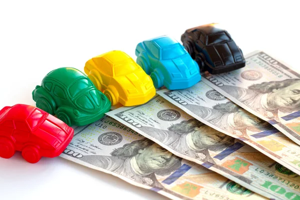 Concept cars and money. Little toy car mock-ups and dollars banknotes on white table. Buying, renting, leasing cars. Investment in a taxi and car park. — Stock Photo, Image