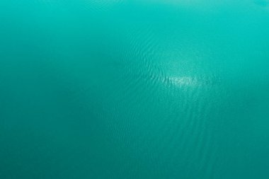 Göl suyunun yüzeyindeki gök mavisi. Tasarım için tropik sakin bir arka plan. Mavi denizin yukarıdan aşağıya dalgalı hava görüntüsü.