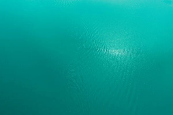 Azur Textura de la superficie del agua del lago. Fondo tropical tranquilo para el diseño. Imagen aérea de arriba a abajo del mar azul con olas . — Foto de Stock