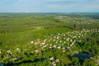 Yeşil orman arasında eko-yerleşim. Banliyölerin yerleşim bölgelerinde çatıları olan evlerin hava görüntüleri. İpotek programı altında inşa edilmiş küçük bir kasaba. Yüksek kalite fotoğraf