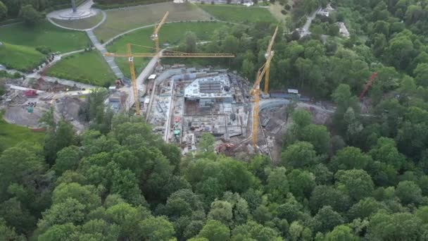 Baustelle mit Baukränen im Park zwischen den Bäumen. Rundumblick aus der Drohne. — Stockvideo