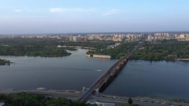 Ukrayna 'nın uzak bir kenti olan Kyiv' in arka planında köprüsü olan geniş nehrin insansız hava aracı görüntüsü. Şehrin akşam manzarası.. 