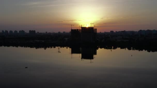 Panorama horizontal da construção com guindastes contra o pano de fundo da paisagem urbana industrial ao amanhecer. Longa distância aérea tiro no drone Mavic 2 Pro . — Vídeo de Stock