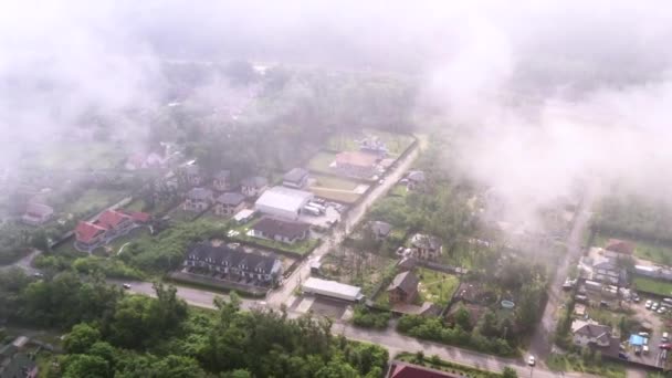 Drone Shot van de omgeving van woonwijken door witte mistige wolken van een grote hoogte. — Stockvideo